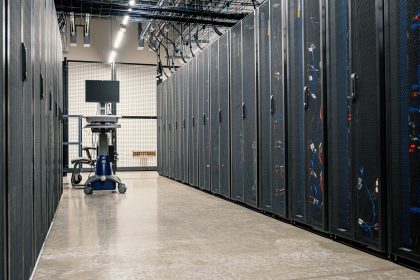 Interior de um datacenter com gabinetes metálicos equipados com servidores, dispositivos de rede e cabos.