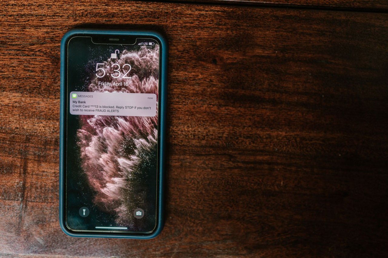 Celular sobre uma superfície de madeira exibindo um alerta bancário.